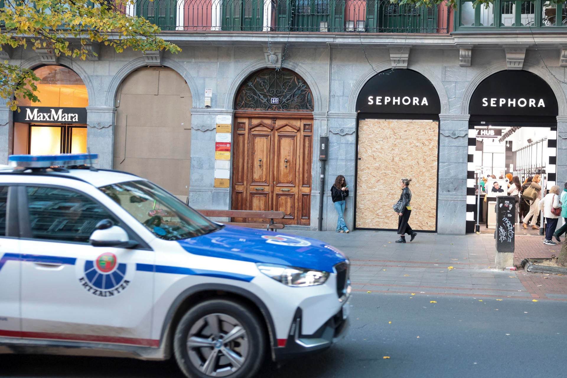 BILBAO, 30/10/2026.-Un coche patrulla de la Ertzaintza ante un comercio donde este viernes los comerciantes del centro de Bilbao y San Sebastián están protegiendo sus escaparates ante la amenaza de posibles saqueos y disturbios alentados para mañana sábado en redes sociales por el movimiento 'Blocus', en un fin de semana en el que hay convocadas en Euskadi una veintena de movilizaciones. EFE/Luis Tejido
