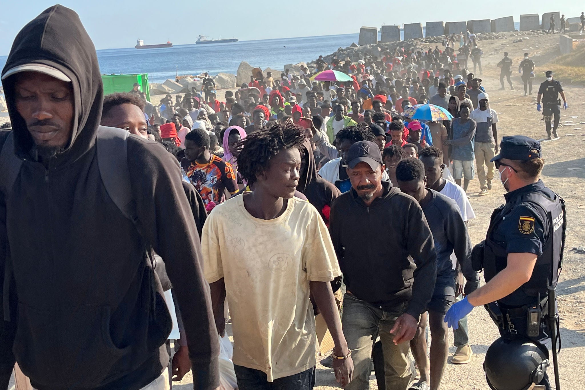CEUTA, 20/08/2026.- Migrantes son desalojados de la playa del Trampolín en Ceuta tras habilitarse un espacio para su acogida este jueves. El Gobierno ha habilitado temporalmente varios espacios para la acogida de 1.800 personas migrantes que se encuentran en situación de calle en la playa del Trampolín y en la zona de Loma Colmenar, en Ceuta, que prevé ampliar progresivamente. EFE/Reduan
