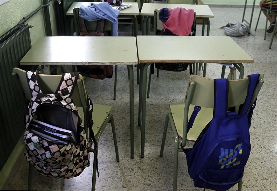 Mochilas colgadas en dos sillas de una aula. Foto de archivo: EFE