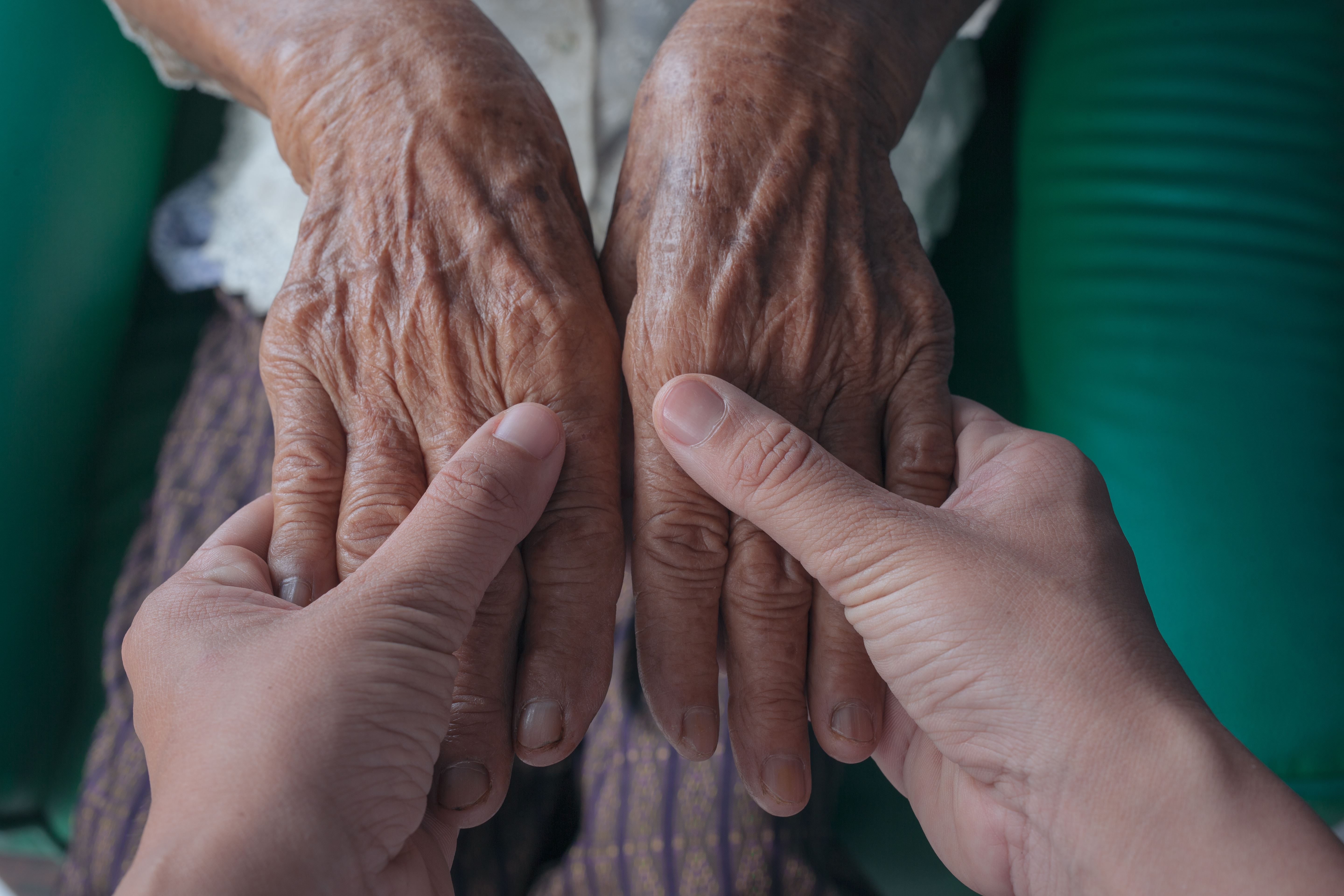 Alzheimerra gazte bat adineko bati eskuak heltzen. CC-BY www.freepik.es