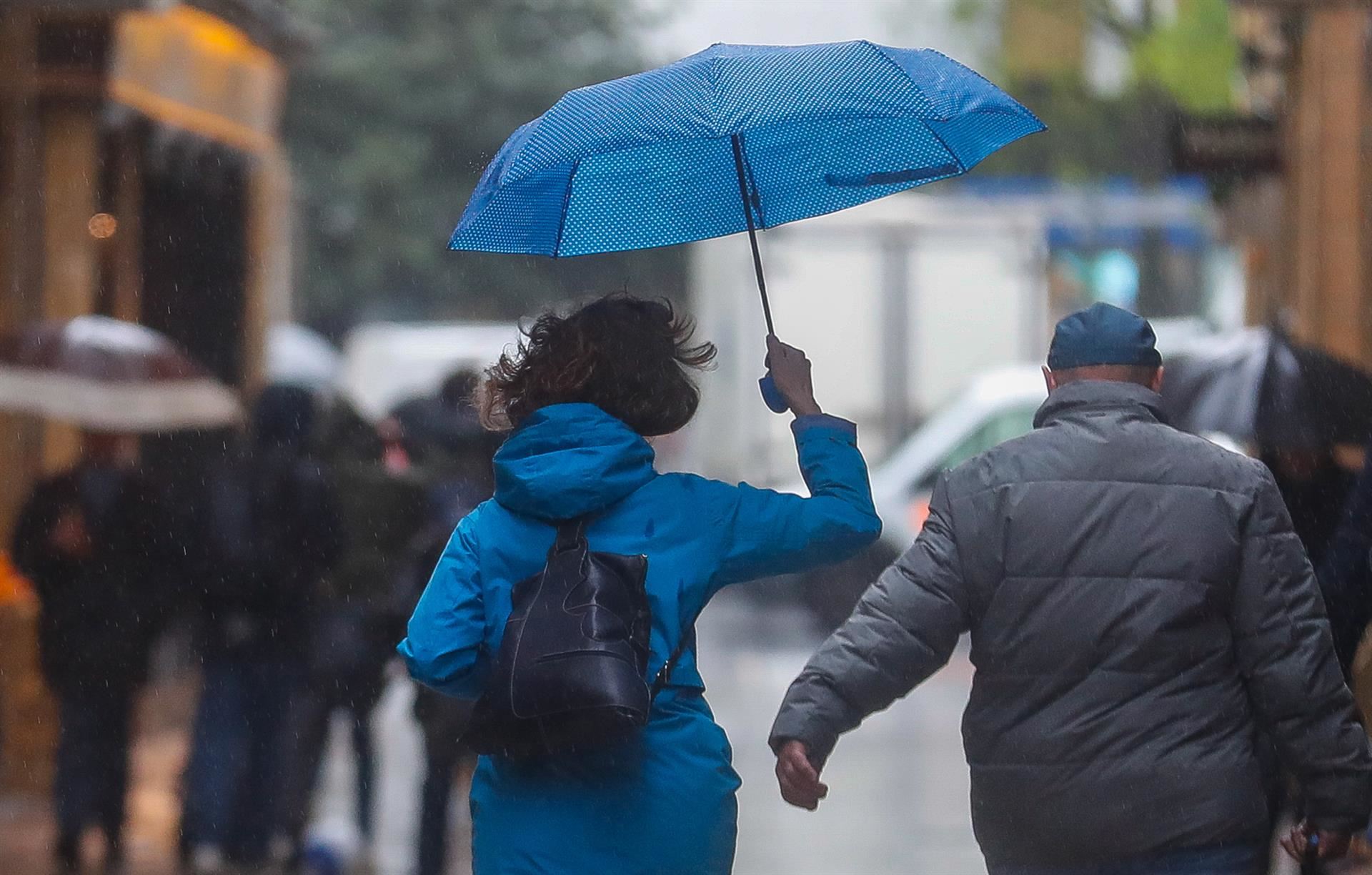 Dos personas caminan bajo la lluvia.