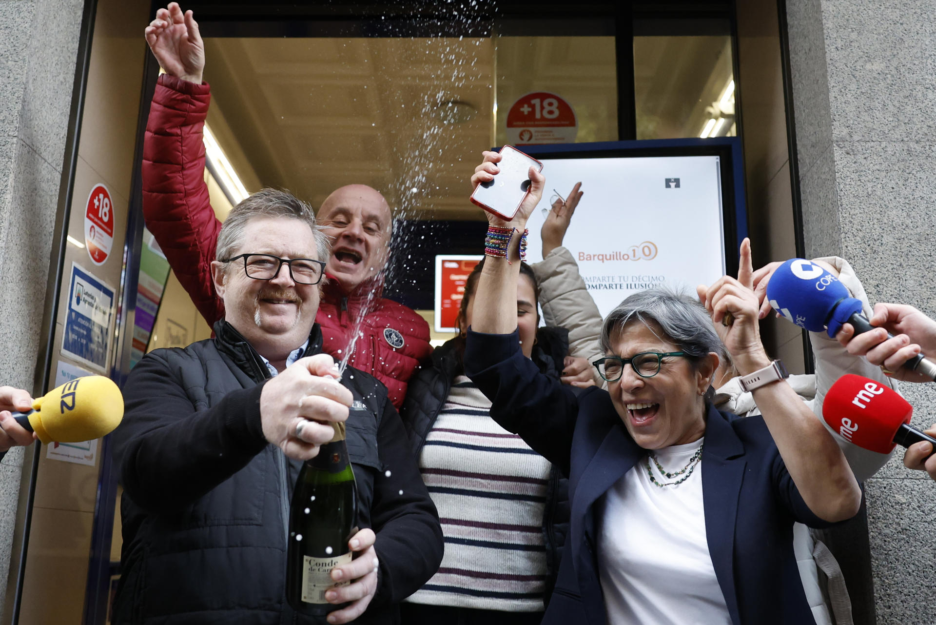 MADRID, 22/12/2025.-Varias personas celebran a las puertas de la administración de loterías del número 10 de la calle Barquillo, en Madrid, donde se ha vendido íntegramente el 70.048, el segundo premio del Sorteo Extraordinario de la Lotería de Navidad. EFE/Mariscal
