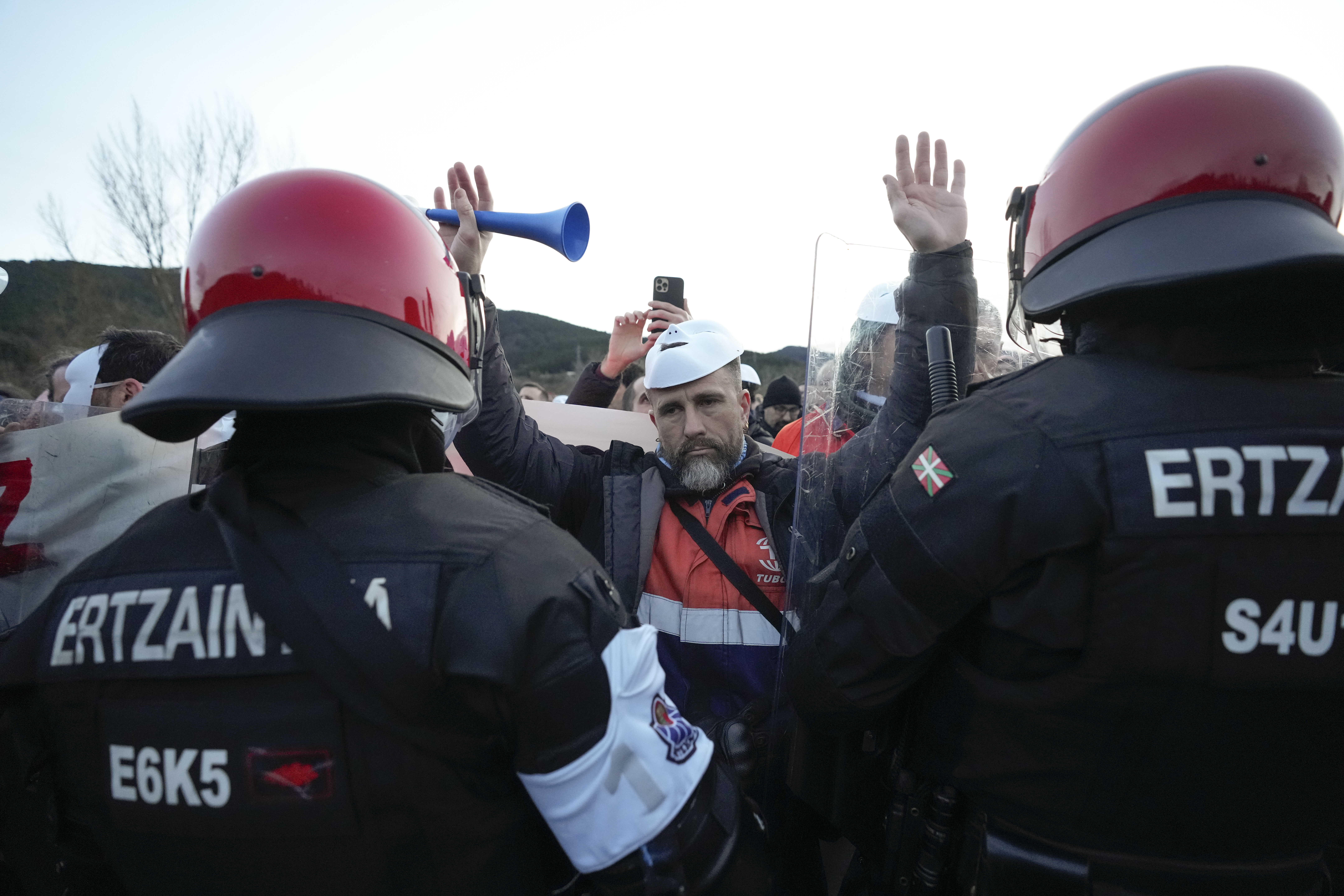 MURRIO (ÁLAVA), 09/02/2026.- Piquetes de trabajadores concentrados tras un cordón de la Ertzaintza en el acceso a la fábrica de Tubos Reunidos en la localidad alavesa de Murrio, este lunes, tras el inicio anoche de una huelga convocada a la espera de conocer el número de afectados por el ERE. EFE/ Adrián Ruiz Hierro
