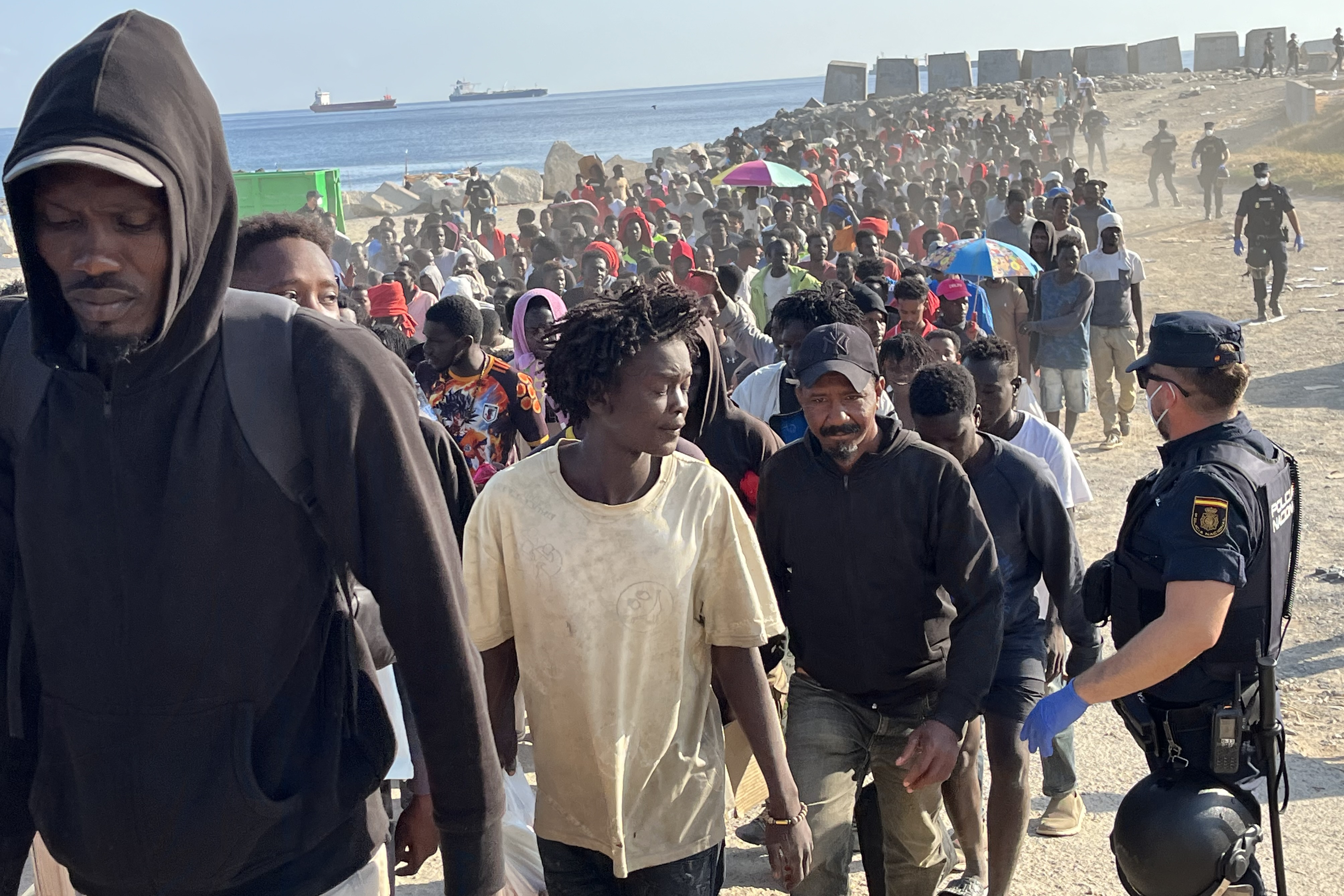CEUTA, 20/08/2026.- Migrantes son desalojados de la playa del Trampolín en Ceuta tras habilitarse un espacio para su acogida este jueves. El Gobierno ha habilitado temporalmente varios espacios para la acogida de 1.800 personas migrantes que se encuentran en situación de calle en la playa del Trampolín y en la zona de Loma Colmenar, en Ceuta, que prevé ampliar progresivamente. EFE/Reduan
