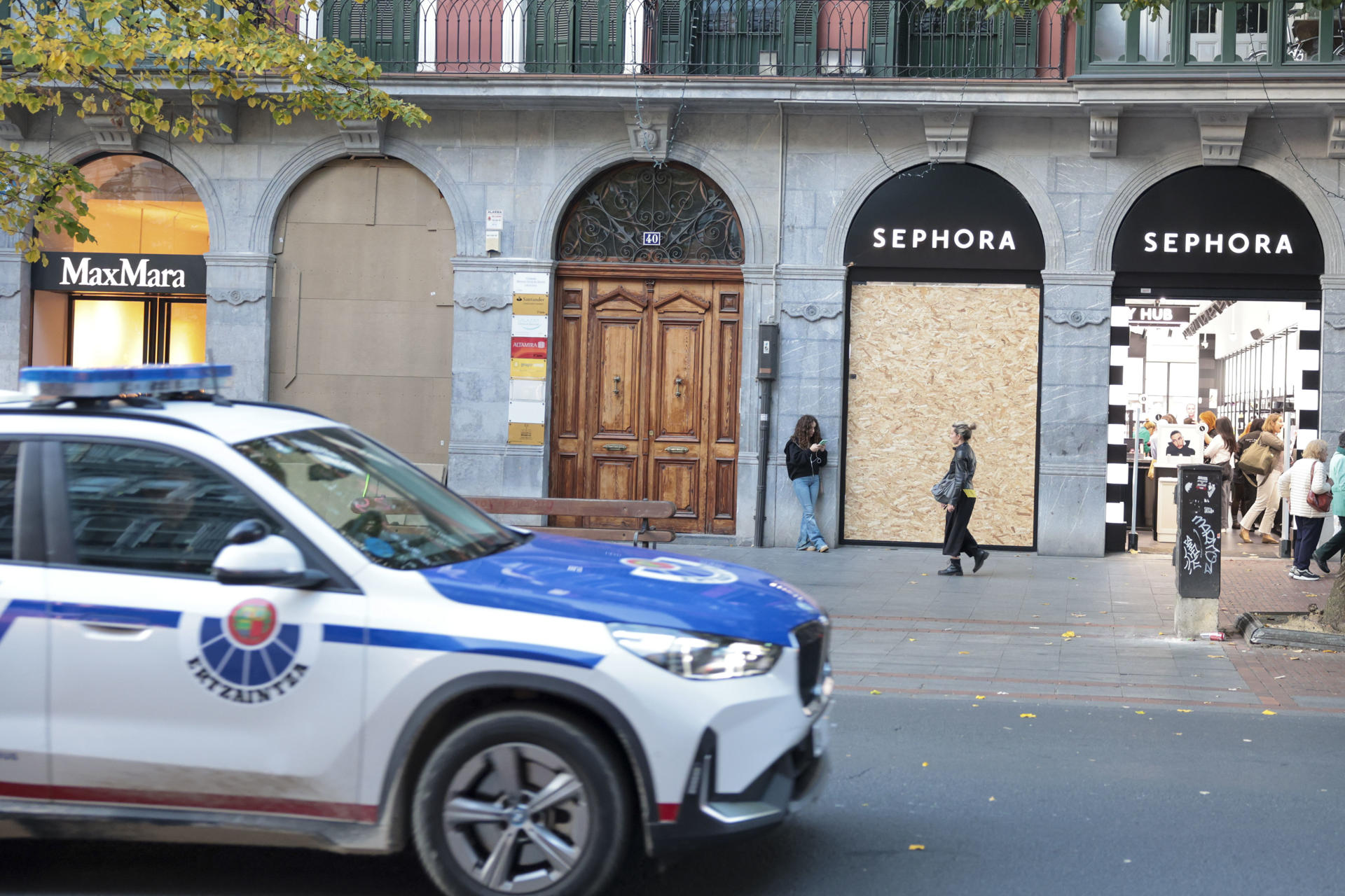 BILBAO, 30/10/2026.-Un coche patrulla de la Ertzaintza ante un comercio donde este viernes los comerciantes del centro de Bilbao y San Sebastián están protegiendo sus escaparates ante la amenaza de posibles saqueos y disturbios alentados para mañana sábado en redes sociales por el movimiento 'Blocus', en un fin de semana en el que hay convocadas en Euskadi una veintena de movilizaciones. EFE/Luis Tejido
